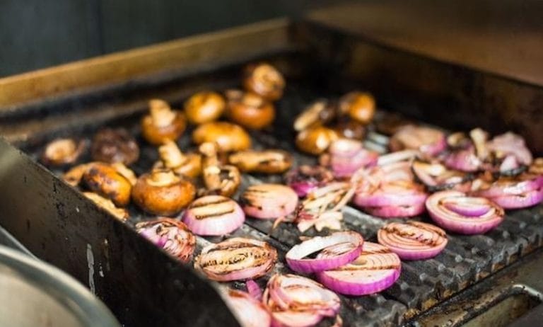 Sliced mushrooms and onions on a grill